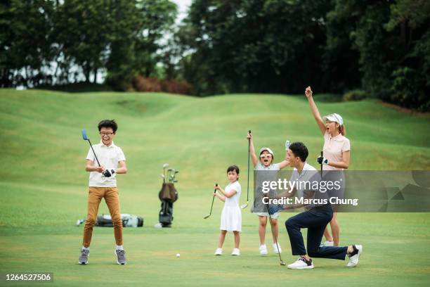 asian chinese smiling family golfer happy and excited after their son tapping in first ball on the golf course - golf shirt stock pictures, royalty-free photos & images