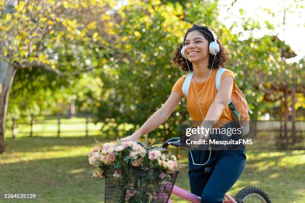 teen girl riding a bicycle in the field - bicycle flowers stock pictures, royalty-free photos & images