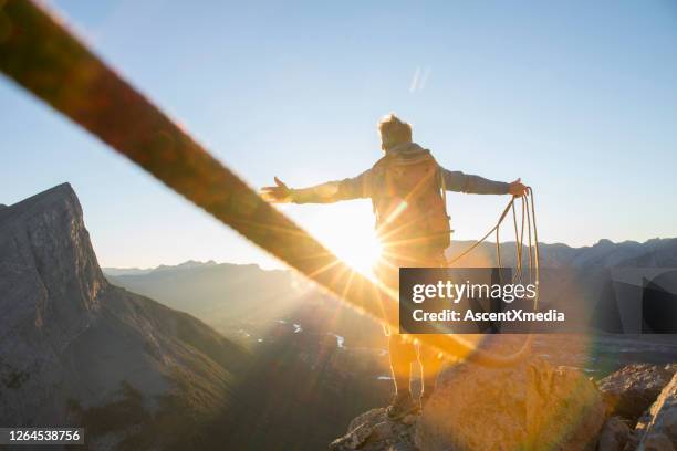 alpinista extiende los brazos para celebrar en la cumbre de la montaña - adrenalina fotografías e imágenes de stock