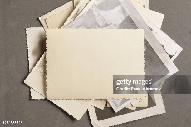 An old faded photo on a stack of old photos on a black page in an old photo album.