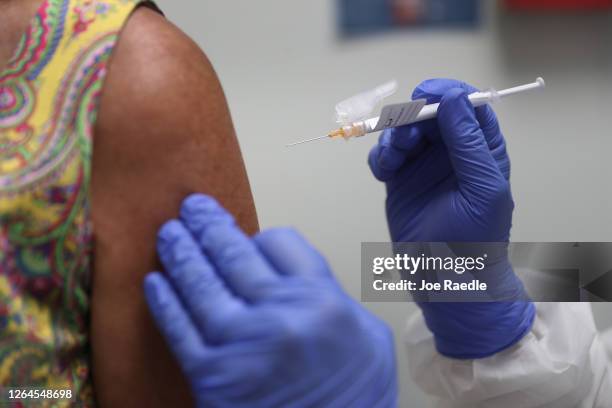 Lisa Taylor receives a COVID-19 vaccination from RN Jose Muniz as she takes part in a vaccine study at Research Centers of America on August 07, 2020...