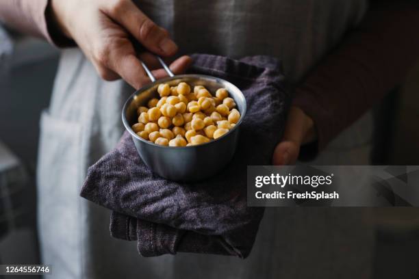 hands of an anonymous woman holding cooked garbanzo beans in a measurement cup - cooking chickpeas stock pictures, royalty-free photos & images