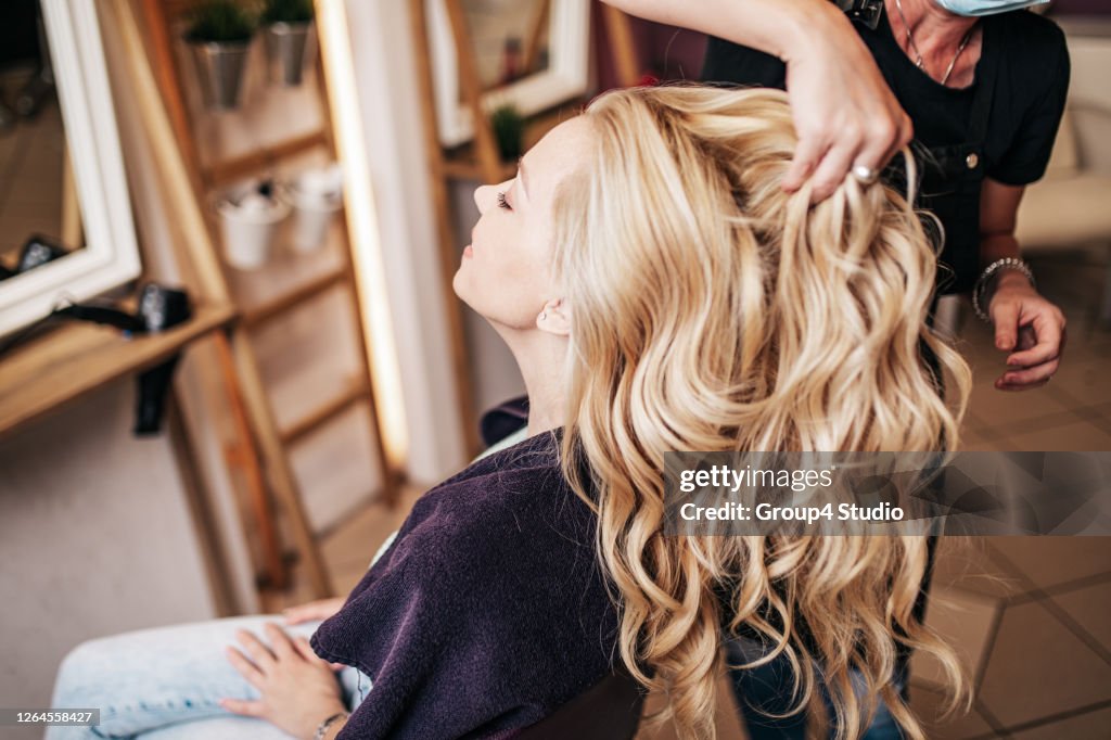 Mujer con mascarilla protectora recibiendo tratamiento en peluquería