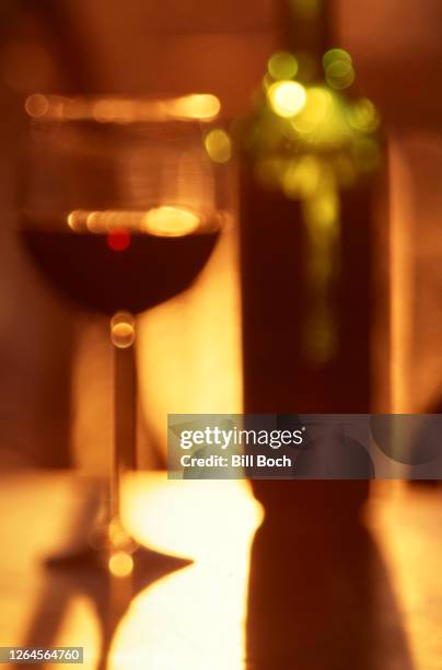 abstract wineglass half full of red wine and the bottle in extreme soft focus - glass half full party stock-fotos und bilder