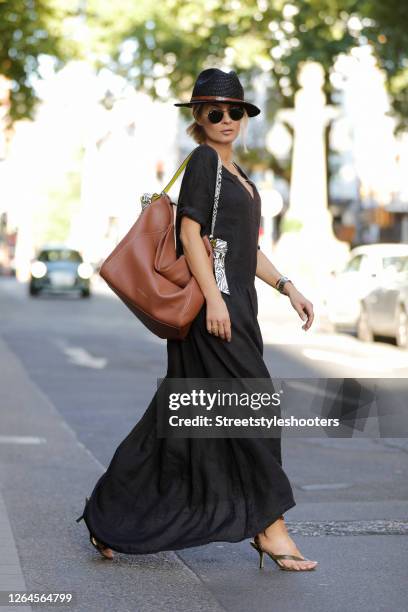 Influencer Gitta Banko wearing a black oversized maxi balloon summer dress by Closed, a black hat, python wrap sandals by Bottega Veneta, sunglasses...