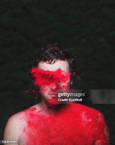 man against a green background looking towards camera with holi powder being thrown at him. - powder throw stock-fotos und bilder