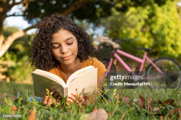 adolescente deitada na grama lendo um livro - poesia literatura - fotografias e filmes do acervo