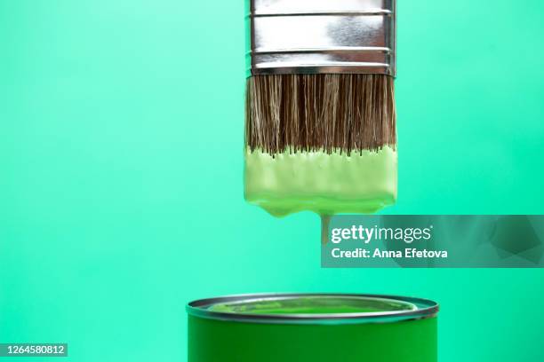 green paint dripping from brush into jar - imagen virada fotografías e imágenes de stock