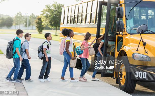 middle school students boarding a bus - school bus stock pictures, royalty-free photos & images