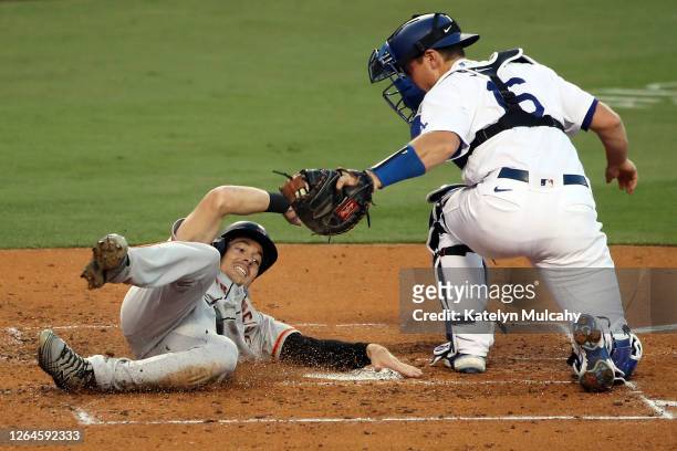 Mike Yastrzemski of the San Francisco Giants slides into home base against Will Smith of the Los Angeles Dodgers during the third inning at Dodger...