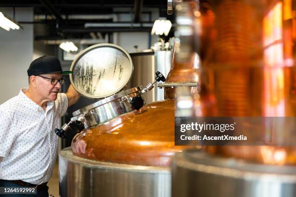 meesterdistilleerder die bij een ambachtelijke distilleerderij werkt - gin stockfoto's en -beelden