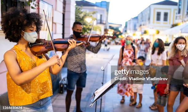 violin players with face masks playing music on the street. - masked musicians stock pictures, royalty-free photos & images