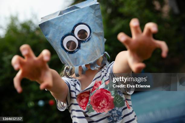 playful child with blue painted paper bag and googly eyes over face - homemade mask stock pictures, royalty-free photos & images