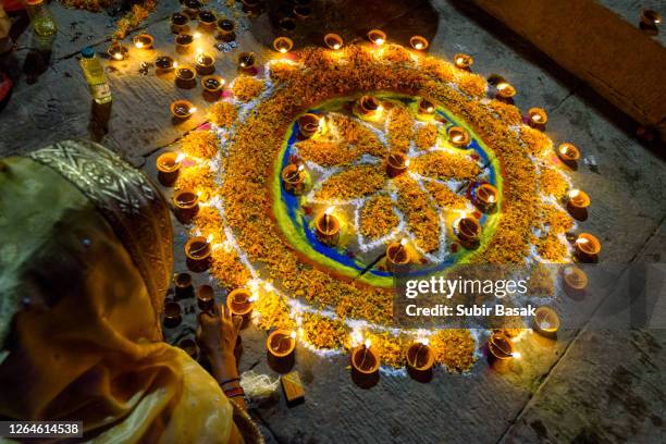 woman hand lighting diyas during diwali,varanasi,uttar pradesh,india. - rangoli stock pictures, royalty-free photos & images