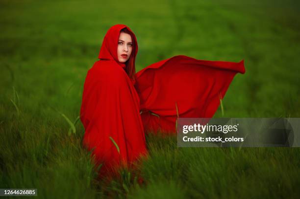 red riding hood in the green field - cape garment stock pictures, royalty-free photos & images