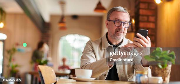 mature man in coffee shop with smartphone - 50s bar stock pictures, royalty-free photos & images