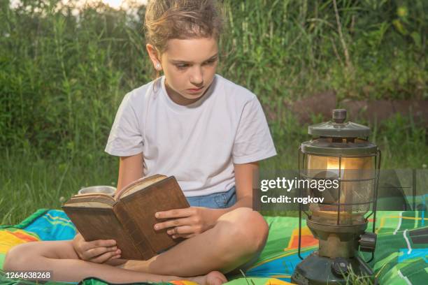 a girl reads a book - children oil lamp study stock pictures, royalty-free photos & images