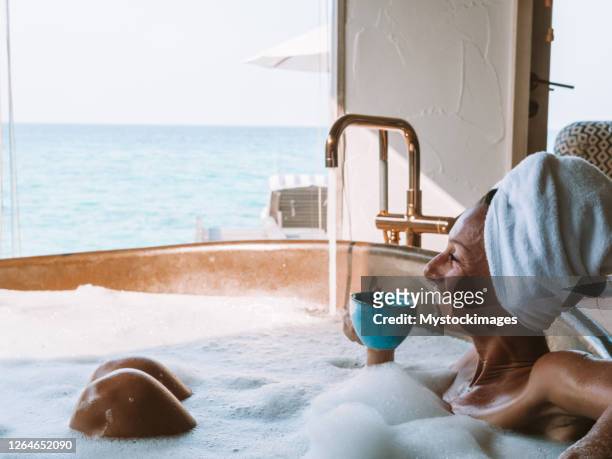 jonge vrouw die een bad in luxe villa over overzees neemt die van een kop koffie geniet - stade francais v bath semi final of european challenge cup stockfoto's en -beelden