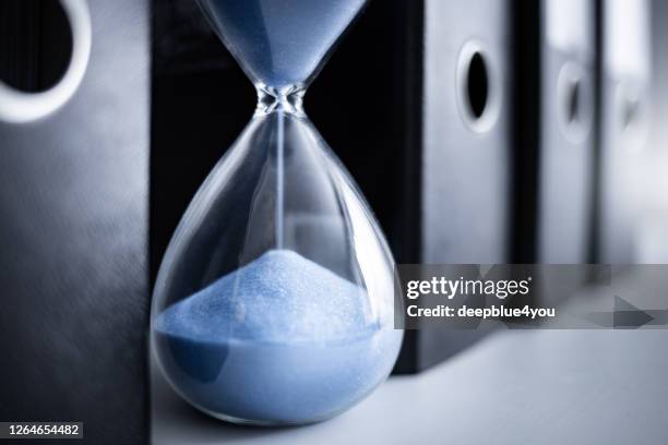 an hourglass runs between file folders - closing time stock pictures, royalty-free photos & images