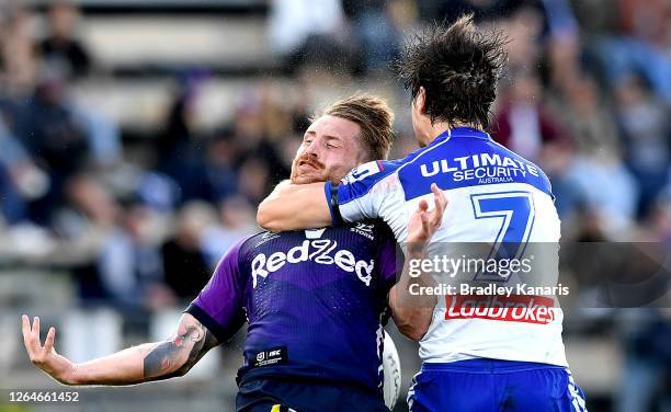 Cameron Munster of the Storm is hit high in the tackle by Lachlan Lewis of the Bulldogs during the round 13 NRL match between the Melbourne Storm and...