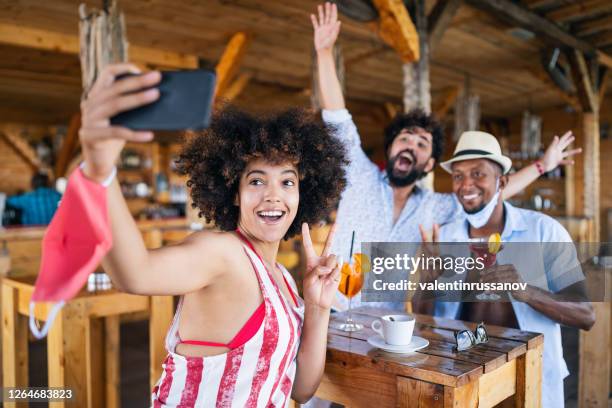 friends drinking cocktail in a restaurant bar in summer days with protective face mask and taking selfie, during covid-19 .reopening concept - bar reopening stock pictures, royalty-free photos & images