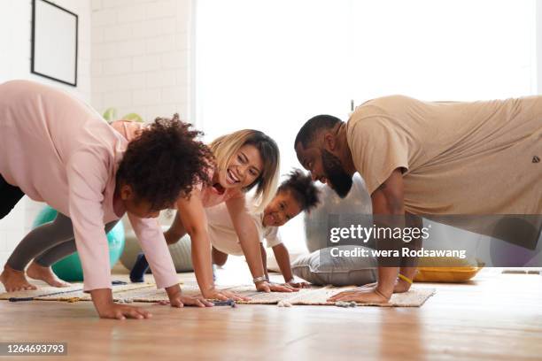 family cheerful laughing exercise together at room - family yoga photos et images de collection