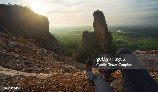 woman hiker on a top of a mountain. fit young woman hiking in the mountains sitting on a rocky summit ridge with backpack and pole looking out over an alpine landscape - hiking pole stock-fotos und bilder