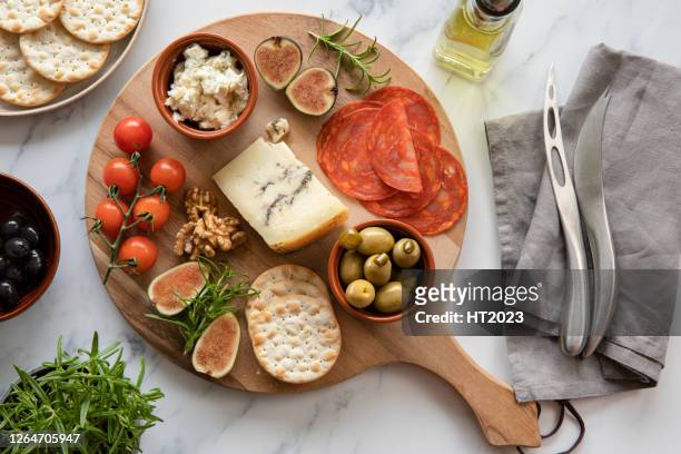 käse, tomaten, chorizo, cracker, oliven auf einem runden holzbrett, teller. - meat platter stock-fotos und bilder