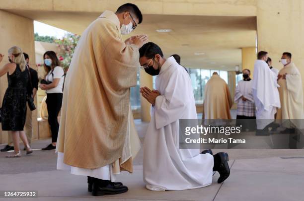 Newly ordained priest Justin Oh gives a first blessing to an altar server following the first-ever outdoor Ordination Mass at the Cathedral of Our...