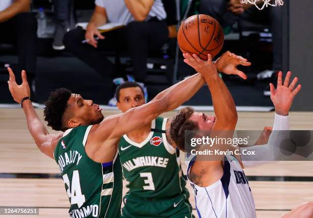 Giannis Antetokounmpo of the Milwaukee Bucks blocks a shot by Luka Doncic of the Dallas Mavericks as George Hill of the Milwaukee Bucks looks on at...