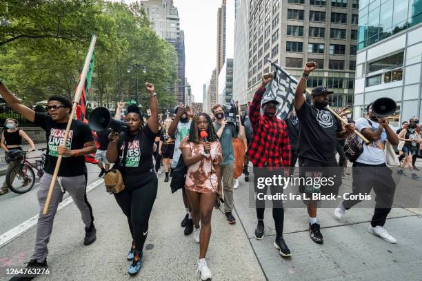 Derrick Ingram holds up fist while marching with Kiara Williams, organizational leader for Warriors in the Garden, Hawk Newsome, Chairperson of Black...