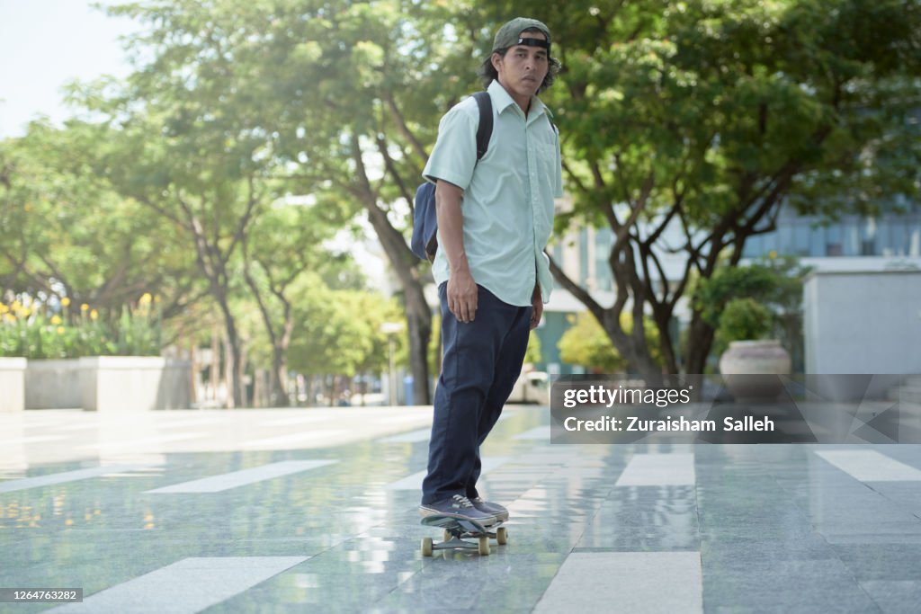 スケートボードで仕事を急ぐアジア人男性