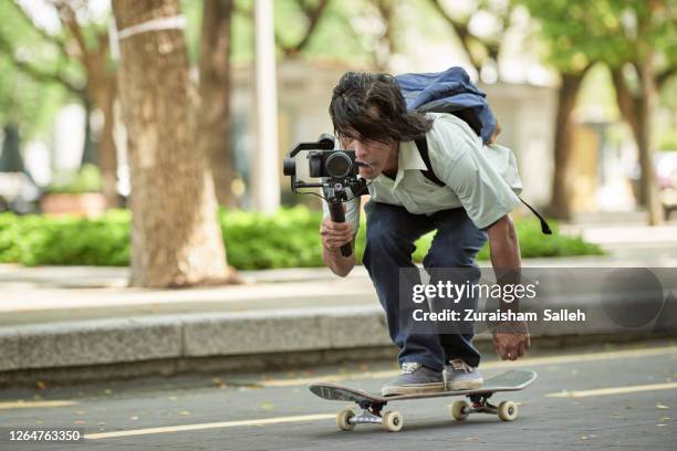 asian skateboarder filming using video recorder with gimbal - cameraman stock pictures, royalty-free photos & images