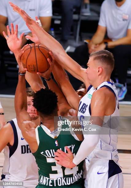 Giannis Antetokounmpo of the Milwaukee Bucks is fouled by Kristaps Porzingis of the Dallas Mavericks while being pressured during overtime at The...