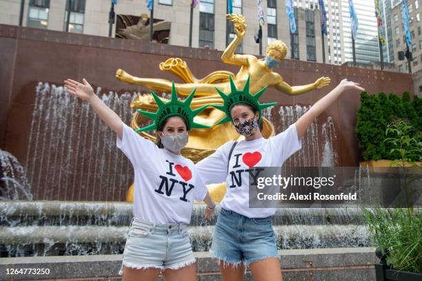 Women wearing masks, 'I love NY' t-shirts and Statue of Liberty head pieces pose in Rockefeller Center as the city continues Phase 4 of re-opening...