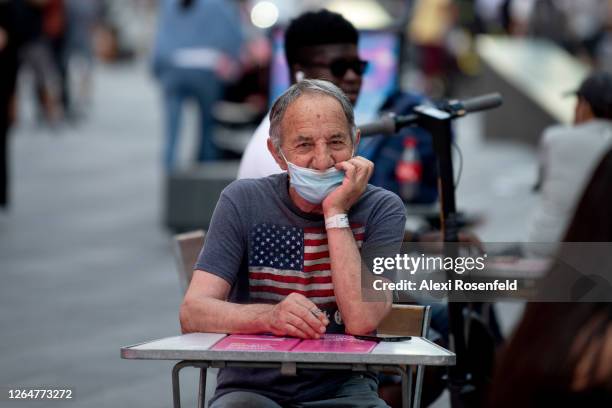 Man wearing a mask below his nose sits at an outdoor table in Times Square as the city continues Phase 4 of re-opening following restrictions imposed...