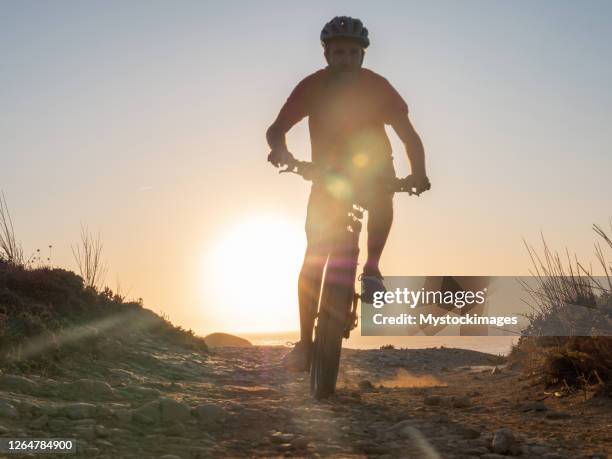 mountain biker riding on the edge of a cliff at sunset - algarve stock pictures, royalty-free photos & images