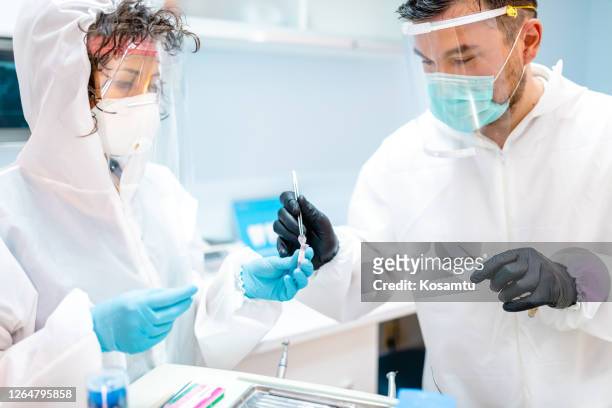 彼のアシスタントが彼の歯科機器を保持している間、内ドン針を選択する専門知識の内ドンティスト - endodontist ストックフォトと画像