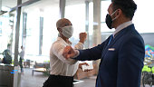 Business people on a safety greeting for covid-19 on office's lobby - with face mask