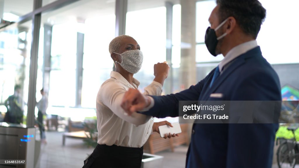 Business people on a safety greeting for covid-19 on office's lobby - with face mask