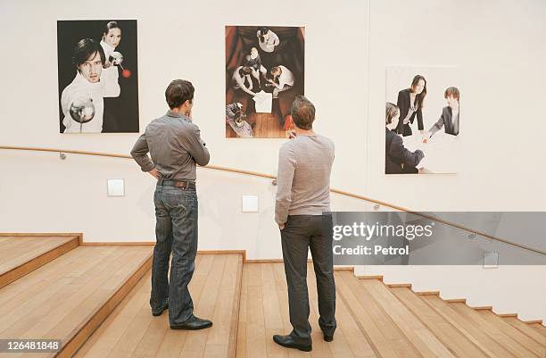 two men looking at photos on wall - looking at art stock pictures, royalty-free photos & images