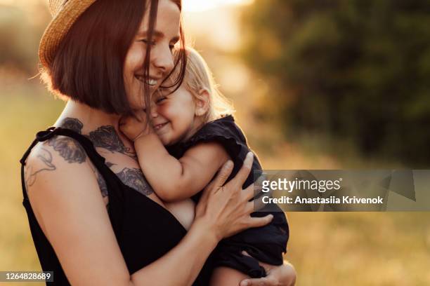 closeup portrait of mother and little daughter playing together in summer park on sunset lights. beauty nature scene with family outdoor lifestyle. happy family concept. - light natural phenomenon foto e immagini stock