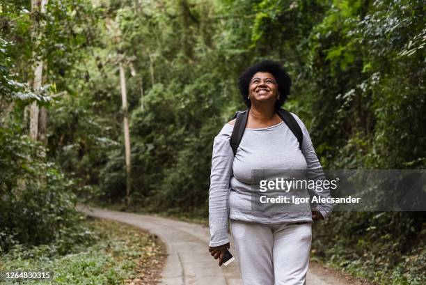 femme de touriste aîné marchant dans le parc de nature - flasque photos et images de collection