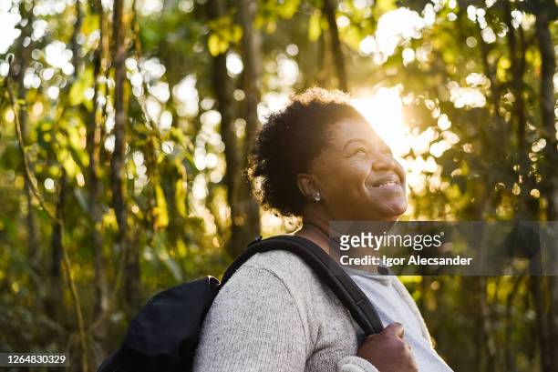 mujer mayor sonriente al atardecer en la naturaleza - turismo ecológico fotografías e imágenes de stock