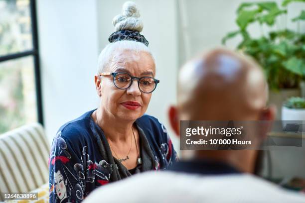 senior woman with hair bun listening to friend - contemplation family imagens e fotografias de stock