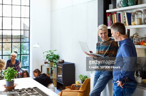 cheerful son with laptop talking to father in kitchen - role model stock pictures, royalty-free photos & images