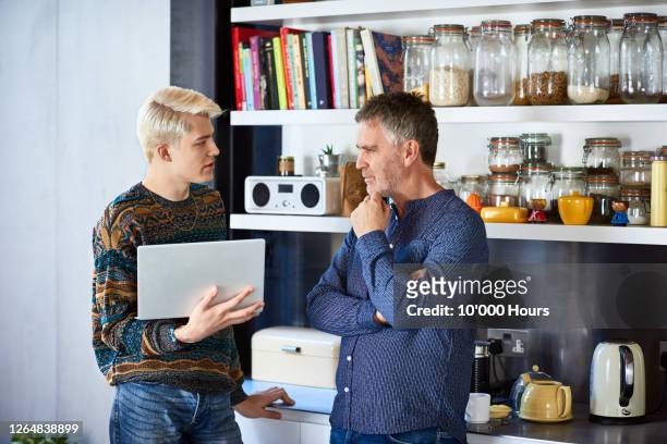 father and adult son discussing with laptop - london not hipster not couple not love not sporty not businessman not businesswoman not young man no stockfoto's en -beelden