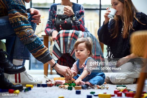 toddler girl playing with toys on floor with adults - bébé jeu photos et images de collection