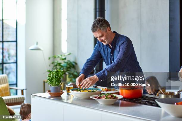 mature man preparing healthy meal on kitchen counter - homme cuisine photos et images de collection