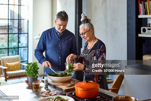 mature man and senior woman making lunch - kochen freunde stock-fotos und bilder